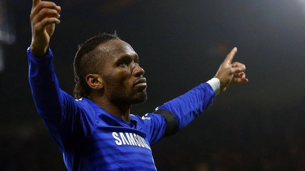 Didier-Drogba-comemorando-com-a-camisa-do-Chelsea-em-arte-destacando-o-placar-de-6-a-0 Hat-tricks na estreia da Premier League: relembre as atuações que marcaram a primeira rodada